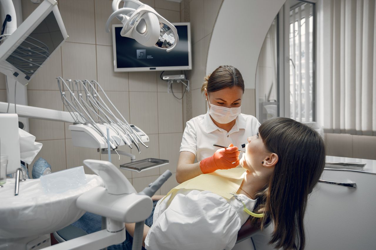 Dentist performing dental examination on female patient in modern clinic.