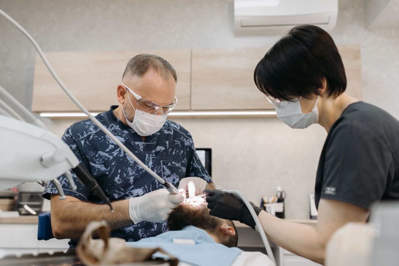 Dentists perform a dental procedure with PPE in a modern clinic setting.